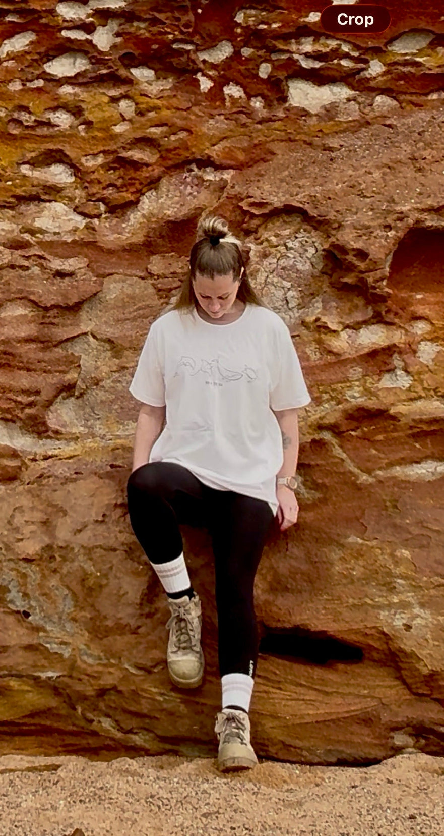 woman leaning against rocks at the beach wearing the vintage white  Marine Life t-shirt in size large